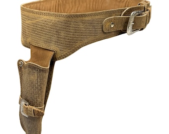 Peut inclure: Une ceinture de pistolet en cuir marron avec une boucle argentée et un holster assorti. La ceinture a un motif tissé et le holster a un rabat avec une boucle argentée.