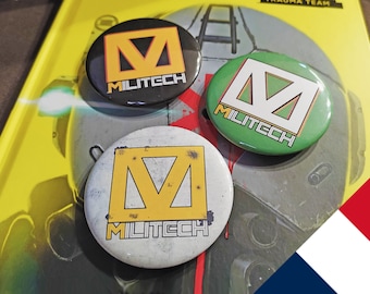 May include: Three round pins with the word "MILITECH" and a stylized "M" logo. The pins are black, green, and white with yellow accents.