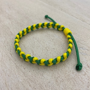 May include: A green and yellow braided bracelet with a knotted end.