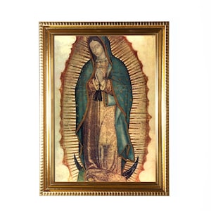 May include: A framed religious image of the Virgin Mary, depicted with a blue cloak and gold accents. The artwork is set against a radiant background and framed in a gold-colored, ornate frame.