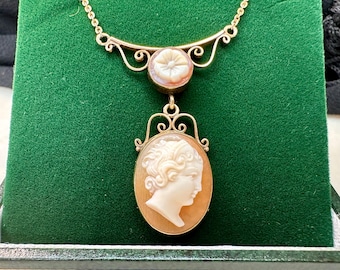 Puede incluir: Un collar de cadena de oro con un colgante de camafeo que presenta el perfil de una mujer y un colgante de camafeo más pequeño con un diseño floral.