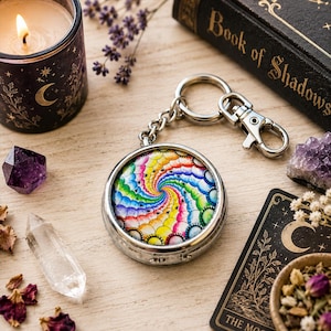 May include: A circular silver keyring featuring a vibrant, multi-coloured spiral pattern under a glass dome. The keyring includes a sturdy metal chain and a lobster clasp, showcasing a repeating rainbow-hued design that radiates from the centre.