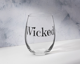 May include: A clear glass wine glass with the word "Wicked" printed on the side in black.