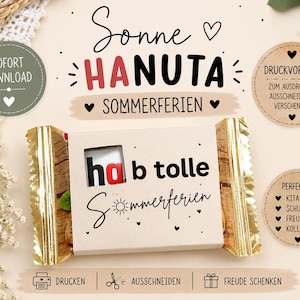 Könnte beinhalten: Eine rechteckige Snack-Verpackung mit einer beigen Papierbanderole, die den Text "hab tolle Sommerferien" und ein Sichtfenster auf das Produkt zeigt. Die Verpackung hat goldfarbene, gezackte Enden und kleine schwarze Herzmotive.
