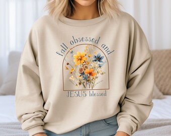May include: Beige sweatshirt with a floral graphic and the text "fall obsessed and JESUS blessed".