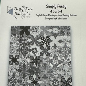 May include: Black and white quilt pattern featuring a repeating star design. The pattern is titled "Simply Fussy" and is 45 inches by 54 inches. The pattern is for English paper piecing or hand sewing. It is designed by Kathi Shunn.