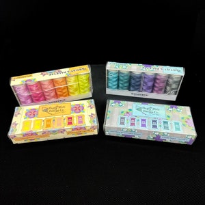 May include: Four boxes of embroidery floss, each containing six spools of thread. The boxes are labeled "Artist's Palette" and feature a floral design. The floss colors are rainbow, teal, purple, and pink.