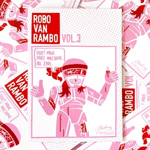 Pode incluir: Uma capa de zine ilustrada em rosa e vermelho com o título "Robo Van Rambo Vol. 3" e o texto "Part man. Part machine. All zine." Um robô rosa com uma faixa vermelha e olhos vermelhos é ilustrado na capa.