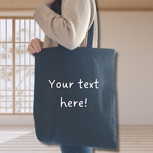 May include: A black tote bag with white text that says "Your text here!"