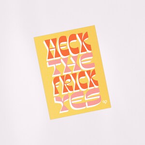 May include: A yellow card with the phrase "Heck the Frick Yes" in orange and pink letters. The letters are stylized with a retro, 70s aesthetic.