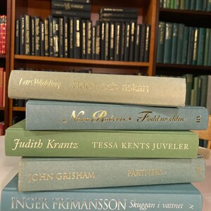 Puede incluir: Una pila de cinco libros de tapa dura con cubiertas verdes y azules. Los títulos son visibles: "Elden och askan", "Född ur elden", "TESSA KENTS JUVELER", "PARTNERS" y "Skuggan i vattnet".