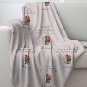 Puede incluir: Una manta suave de color beige con un patrón repetido de un cerebro estilizado con flores y el texto "NURSE PSYCHIATRIC PRACTITIONER" y "Julie".