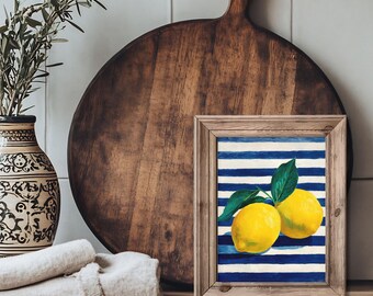 Puede incluir: Una impresión artística enmarcada con dos limones amarillos con hojas verdes sobre un fondo a rayas azules y blancas. La impresión está en un marco de madera rústico, exhibida sobre una superficie de madera con un jarrón decorativo y una tabla de cortar.
