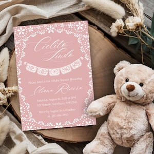 Könnte beinhalten: Rosafarbene Babyparty-Einladung mit weißem Spitzenrand und dem Text "Cielito Lindo" in Kursivschrift. Die Einladung enthält den Namen "Olivia Rivera", das Datum und die Uhrzeit der Party sowie die Adresse. RSVP-Informationen sind ebenfalls enthalten.