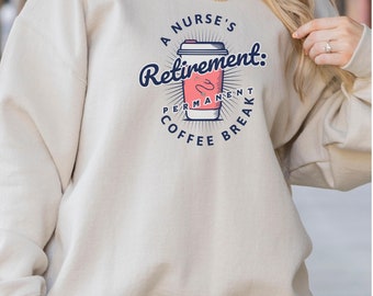 Puede incluir: Una sudadera beige con un diseño gráfico de una taza de café con el texto "A Nurse's Retirement: Permanent Coffee Break".