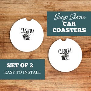May include: Two white car coasters with a custom logo design. The coasters have a semi-circle cutout and are displayed on a wooden surface. Text on the image reads "Soap Stone Car Coasters" and "Set of 2 Easy to Install."
