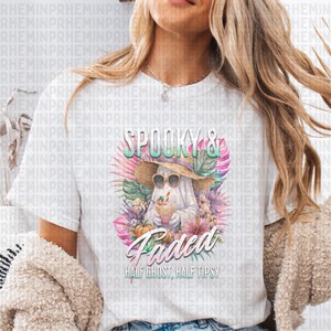 May include: White t-shirt featuring a ghost wearing sunglasses and a straw hat, holding a drink. The shirt has the words "Spooky & Faded" and "Half Ghost, Half Tipsy" printed on it, surrounded by tropical flowers.
