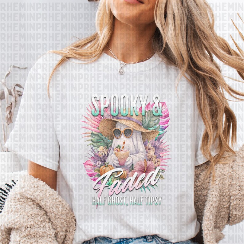 May include: White t-shirt featuring a ghost wearing sunglasses and a straw hat, holding a drink. The shirt has the words "Spooky & Faded" and "Half Ghost, Half Tipsy" printed on it, surrounded by tropical flowers.