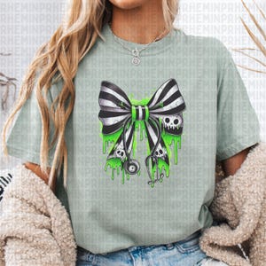 Op de afbeelding: Lichtgroen t-shirt met een zwart-wit gestreepte strik, een groen midden en druipend groen slijm. De strik heeft twee schedels en een stethoscoop. Het t-shirt heeft een casual stijl.