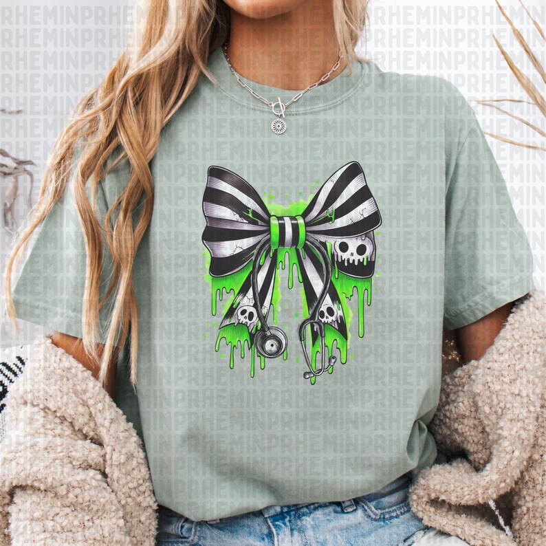 Op de afbeelding: Lichtgroen t-shirt met een zwart-wit gestreepte strik, een groen midden en druipend groen slijm. De strik heeft twee schedels en een stethoscoop. Het t-shirt heeft een casual stijl.