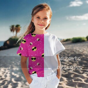 May include: A young person wearing a short-sleeved t-shirt. The shirt is split down the middle, with a white panel on the right and a pink panel on the left. The pink panel has a pattern of yellow smiley faces wearing sunglasses and lollipops.