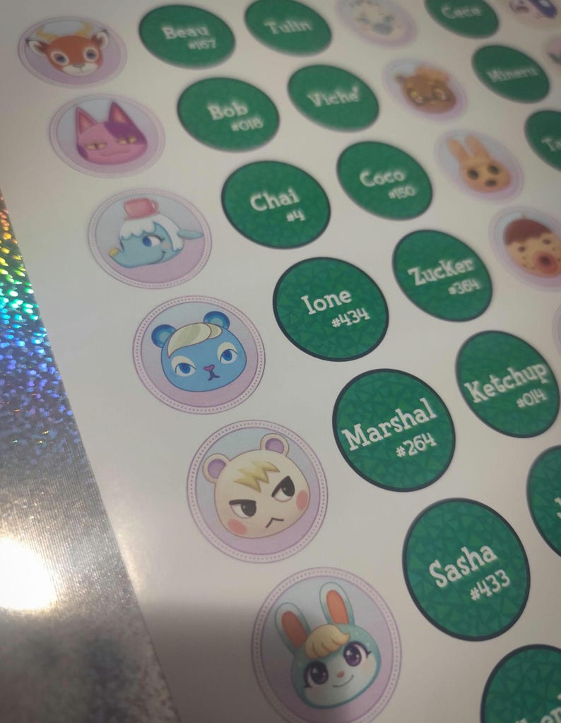 May include: A sticker sheet featuring circular designs with Animal Crossing character faces on light purple backgrounds and green circles with white text displaying names like Beau, Bob, Chai, Ione, Marshal, and Sasha alongside their specific ID numbers.