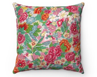 Könnte beinhalten: Quadratisches Zierkissen mit einem lebendigen Blumenmuster. Das Design zeigt eine dichte Anordnung farbenfroher Blumen in Rosa-, Rot-, Orange-, Gelb- und Blautönen vor hellem Hintergrund. Das Kissen ist ein dekoratives Wohnaccessoire.