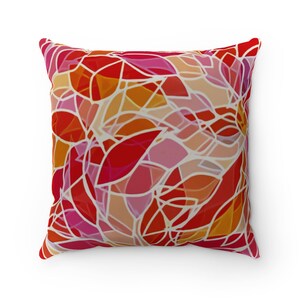 Könnte beinhalten: Quadratisches Zierkissen mit einem lebendigen abstrakten Design. Das Kissen zeigt ein mosaikartiges Muster aus roten, rosa, orangefarbenen und pfirsichfarbenen Formen, die mit weißen Linien umrandet sind. Das Kissen ist quadratisch und scheint aus einem weichen Stoff zu sein.