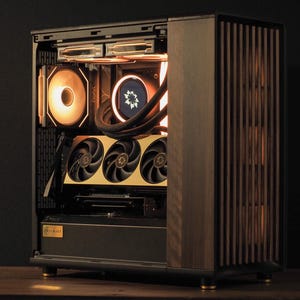 May include: A custom-built computer case with a wooden front panel and internal components illuminated by warm lighting. The case features a gold-colored graphics card with three fans, and a circular fan with a floral design.