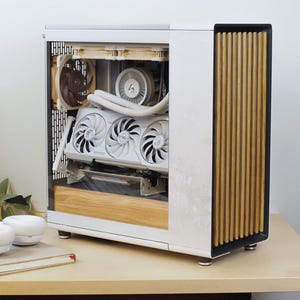 May include: A white computer case with a wooden front panel and internal components visible. The case features a glass side panel, showcasing fans, a graphics card, and a liquid cooling system. The case sits on a light-colored desk.