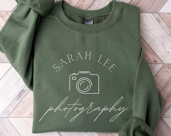 May include: A green sweatshirt with the text "SARAH LEE photography" and a camera icon in white.
