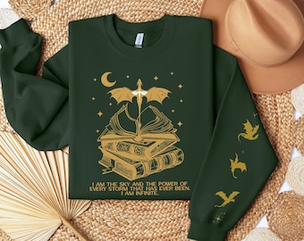 Può includere: Una felpa verde scuro con un drago dorato che vola sopra una pila di libri. Il testo sulla felpa recita "Sono il cielo e il potere di ogni tempesta che sia mai stata. Sono infinito."