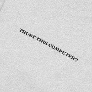 Könnte beinhalten: Ein graues T-Shirt mit dem Aufdruck "TRUST THIS COMPUTER?" auf der Vorderseite.