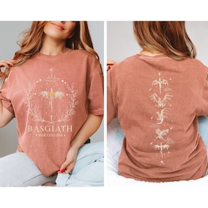 May include: Terracotta-coloured t-shirt. The front features a dragon design and the text "BASGIATH WAR COLLEGE" within a wreath. The back displays a vertical series of dragon illustrations in a light colour.