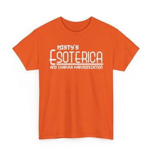 Peut inclure: T-shirt orange avec l'inscription blanche "Misty's Esoterica and Chakra Harmonization". Le texte est centr&eacute;. Le t-shirt &agrave; manches courtes est de couleur orange vif, id&eacute;al pour un look d&eacute;contract&eacute;.