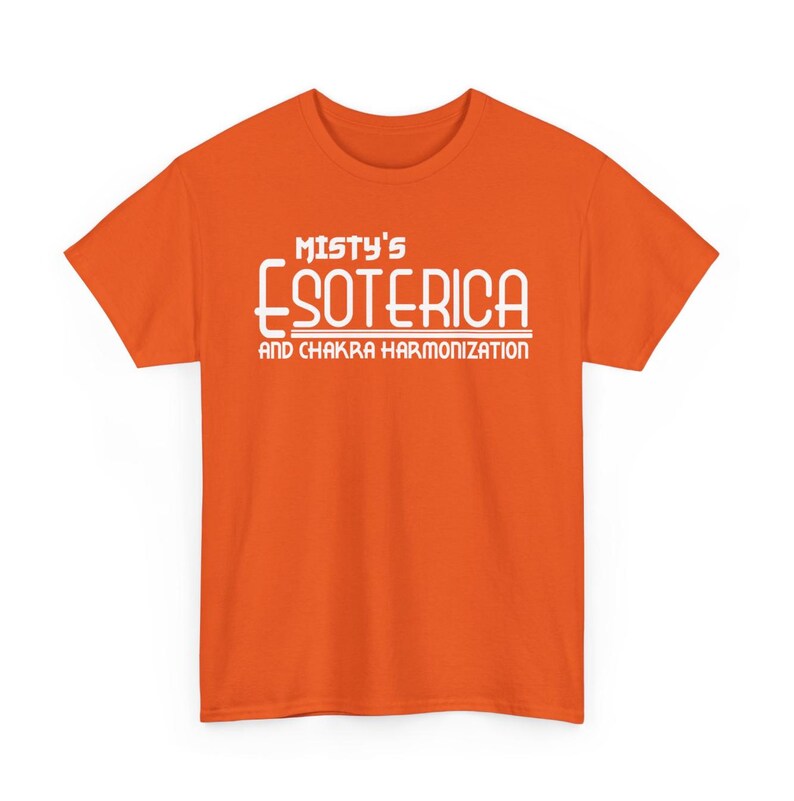 Peut inclure: T-shirt orange avec l'inscription blanche "Misty's Esoterica and Chakra Harmonization". Le texte est centr&eacute;. Le t-shirt &agrave; manches courtes est de couleur orange vif, id&eacute;al pour un look d&eacute;contract&eacute;.