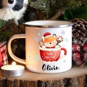 May include: White enamel mug with a red and white illustration of a fox in a mug with the text "Merry Christmas" and the name "Olivia" printed on the bottom.