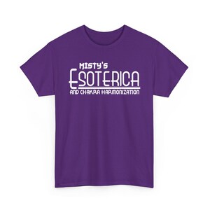 Peut inclure: T-shirt violet avec l'inscription blanche "Misty's Esoterica and Chakra Harmonization". Le texte est centr&eacute; sur le devant. Le t-shirt a des manches courtes et un col rond.