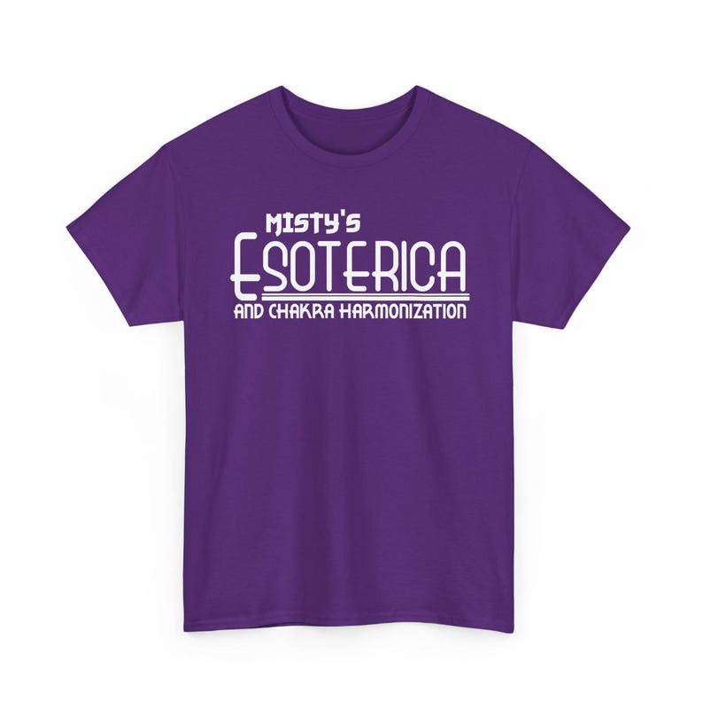 Peut inclure: T-shirt violet avec l'inscription blanche "Misty's Esoterica and Chakra Harmonization". Le texte est centr&eacute; sur le devant. Le t-shirt a des manches courtes et un col rond.
