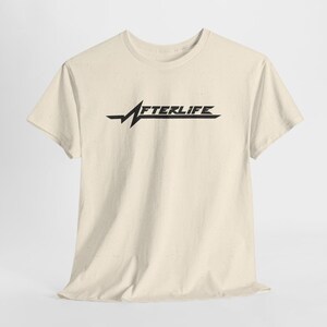 May include: Cream-colored t-shirt featuring the word "AFTERLIFE" in a stylized black font. The design includes a horizontal line with a jagged, lightning bolt-like element. The shirt has short sleeves and a crew neck.
