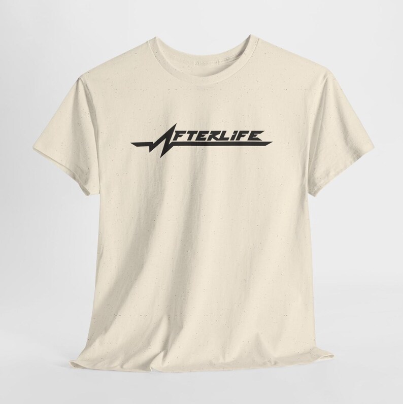 May include: Cream-colored t-shirt featuring the word "AFTERLIFE" in a stylized black font. The design includes a horizontal line with a jagged, lightning bolt-like element. The shirt has short sleeves and a crew neck.