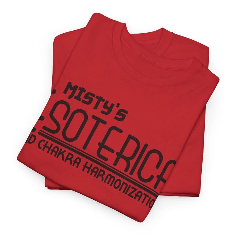 Peut inclure: Deux t-shirts rouges pli&eacute;s. Le t-shirt sup&eacute;rieur porte l'inscription noire "Misty's Soteric", avec "and Chakra Harmonization" en dessous. Les t-shirts sont en mati&egrave;re souple et sont probablement pour un usage d&eacute;contract&eacute;.