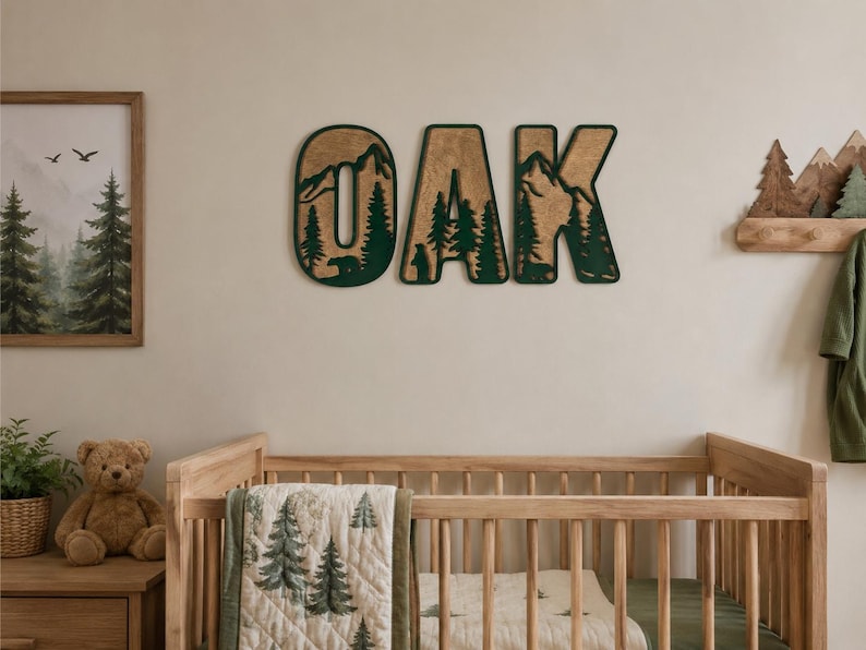 May include: Three large wooden wall letters spelling OAK, featuring a layered design with a natural wood grain finish and a dark green forest silhouette cutout. Each letter displays a detailed mountain landscape with pine trees and a bear.