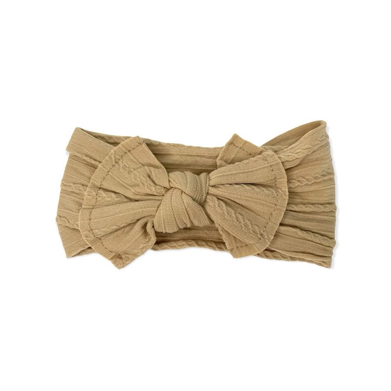 May include: A tan knotted headband with a cable knit texture. The headband is made of a soft, stretchy fabric.