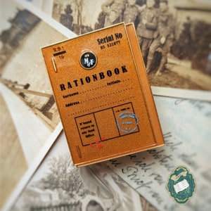 May include: A brown ration book with gold edging, featuring the text "RATIONBOOK" and spaces for details. It includes a "County Food U.S. Food" stamp and the serial number "BS 521677". The book is reminiscent of wartime rationing.
