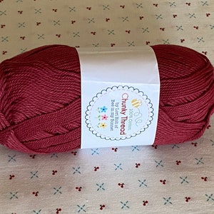 May include: A ball of deep red chunky cotton yarn with a white label that reads "100% Cotton Chunky Thread by Lori Holt of Bee in my Bonnet".