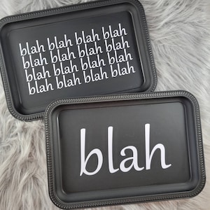 May include: Two black trays with white lettering. The larger tray says "blah blah blah blah blah blah blah blah blah blah" and the smaller tray says "blah".