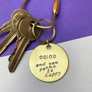May include: Brass keychain with a round tag that says "00:00 and you gonna be happy".