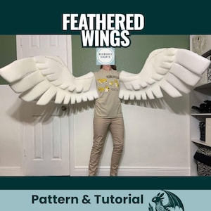 Puede incluir: Grandes alas blancas con plumas y un diseño en capas. Las alas se muestran sobre un fondo neutro. El texto "FEATHERED WINGS" está en la parte superior y "Pattern & Tutorial" en la inferior.