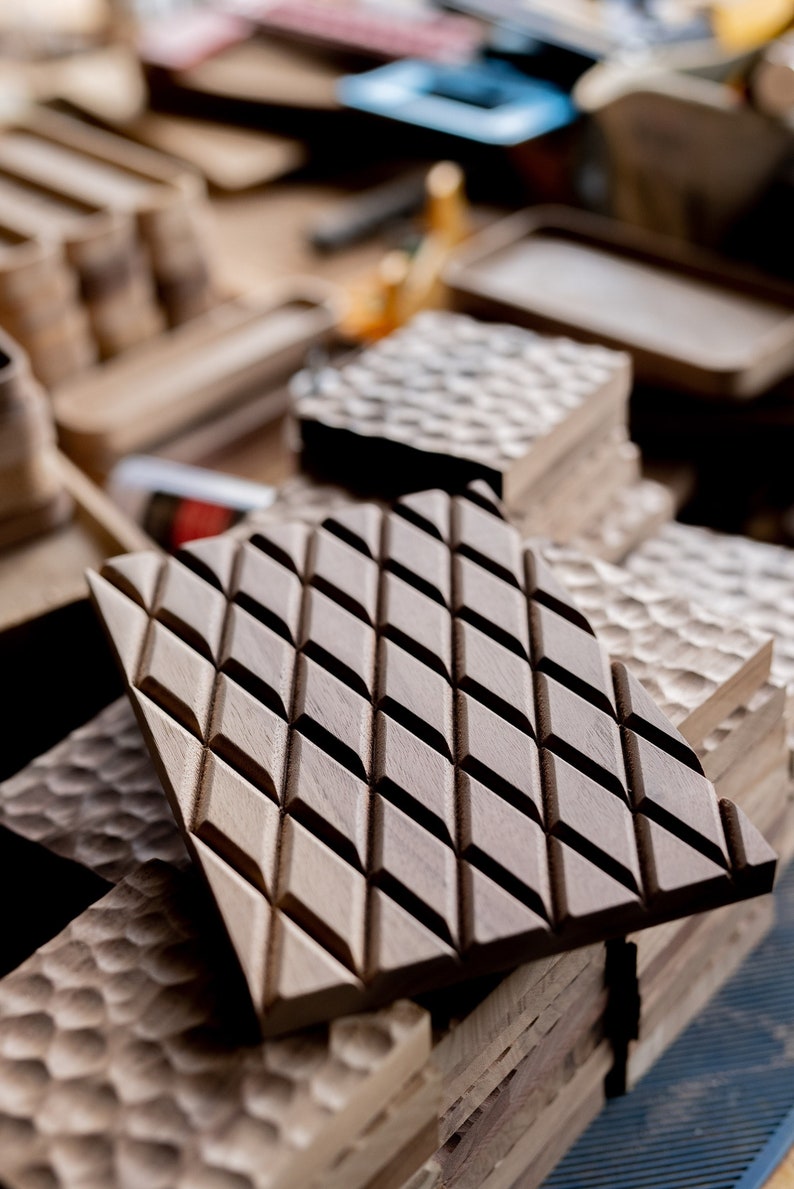 May include: A close-up of a stack of wooden tiles with a diamond pattern. The tiles are made of dark wood and have a smooth, polished finish.